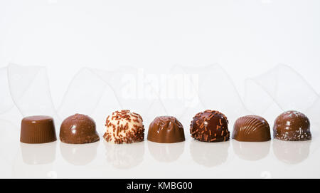 Chocolate pralines in a row with transparent white ribbon, text space Stock Photo