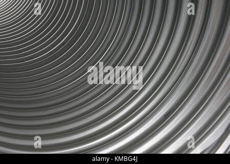 Inside of a corrugated aluminum metal pipe with a pattern of curved lines and textures Stock Photo