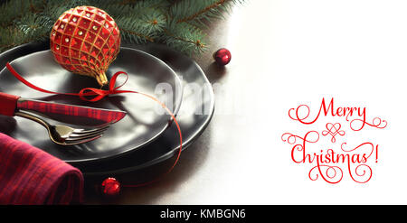 Christmas menu concept with black plates and cutlery decorated with Christmas tree twigs and baubles, isolated on white, text space Stock Photo