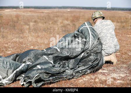 U.S. Army Sgt. Micah Moore 16th Military Police Brigade 501st Airborne, returns after completing his jump in participation for the 20th Annual Randy Oler Memorial Operation Toy Drop, hosted by U. S. Army Civil Affairs & Psychological Operations Command (Airborne),  Dec. 1, 2017 on Sicily Drop Zone at Fort Bragg, North Carolina. Operation Toy Drop is the world’s largest combined airborne operation with nine partner nation paratroopers participating and allows Soldiers the opportunity to train on their military occupational specialty, maintain their airborne readiness, and give back to the local Stock Photo