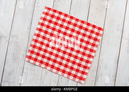 Red tablecloth on white wooden table background. Stock Photo