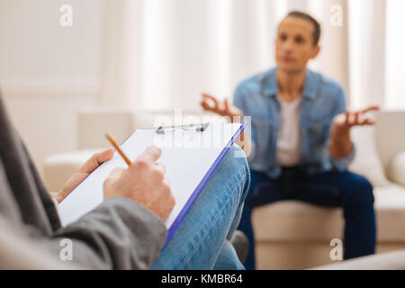 Male psychologist taking notes during therapy session  Stock Photo