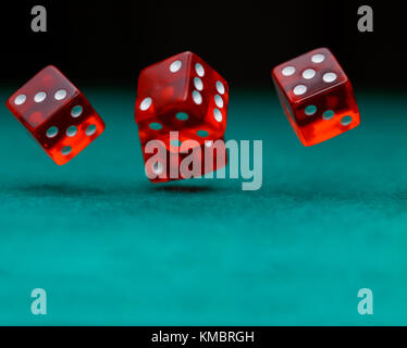 Photo of several red dice falling on green table on black background Stock Photo