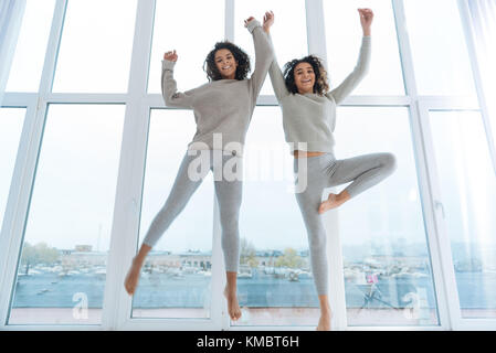 Excited sisters in casual jumping high together Stock Photo