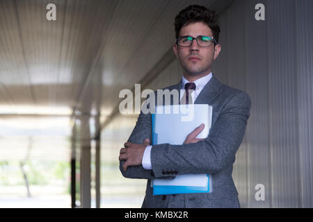 Portrait serious businessman holding paperwork in office corridor Stock Photo