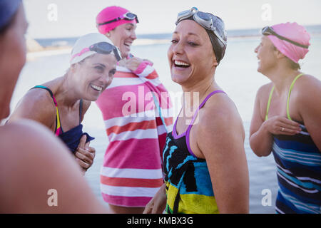 Laughing female open water swimmers drying off with towels Stock Photo