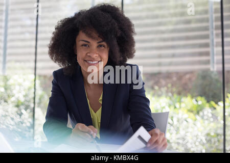 Portrait smiling, confident businesswoman reviewing paperwork Stock Photo
