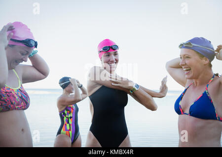 Smiling female open water swimmers stretching and preparing Stock Photo