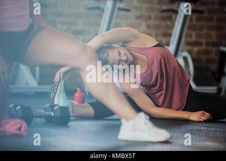 Young woman stretching legs and side in gym Stock Photo