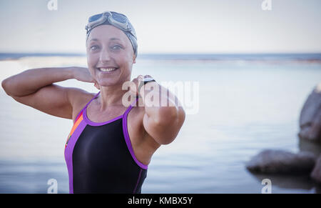 Portrait smiling female open water swimmer adjusting bathing suit in ocean Stock Photo