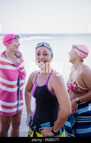 Portrait smiling, confident female open water swimmers drying off with towels at ocean Stock Photo