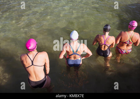 Overhead view female open water swimmers wading in ocean Stock Photo