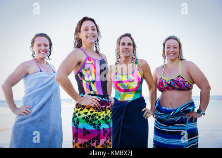 Portrait confident, smiling female open water swimmers wrapped in towels Stock Photo