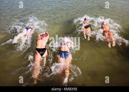 Overhead view female open water swimmers swimming in sunny ocean Stock Photo