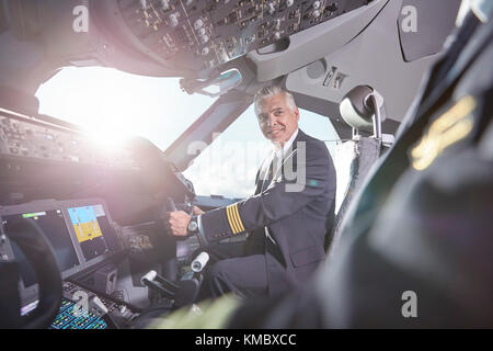 Smiling pilots talking in airplane cockpit Stock Photo