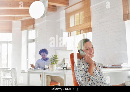 Businesswoman talking on cell phone in office Stock Photo