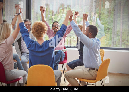 People holding hands in circle in group therapy session Stock Photo