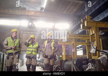 Steelworkers walking and talking in steel mill Stock Photo