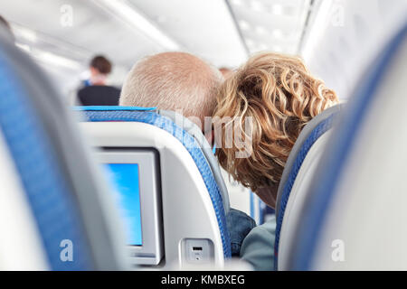 Rear view affectionate mature couple leaning on airplane