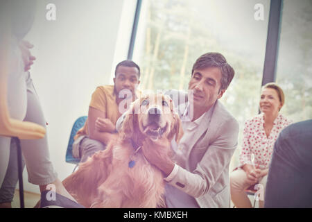 Man petting dog in group therapy session Stock Photo