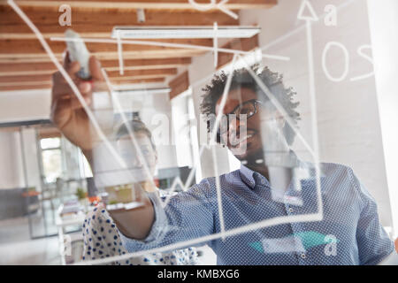 Business people drawing graph on window in office Stock Photo