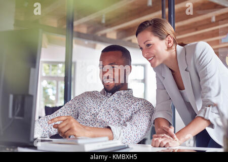 Businessman and businesswoman working at computer in office Stock Photo