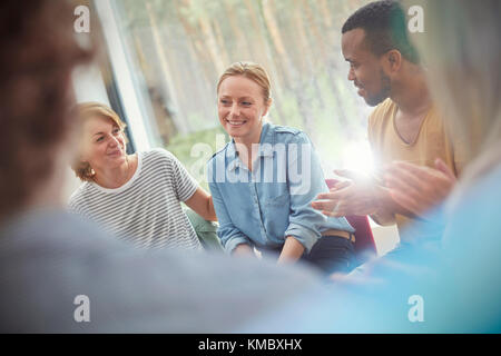 People clapping for woman in group therapy session Stock Photo