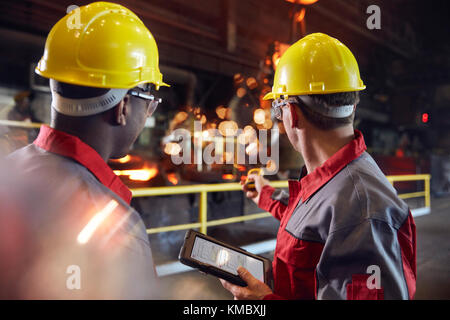 Supervisor and steel worker with digital tablet working in steel mill Stock Photo