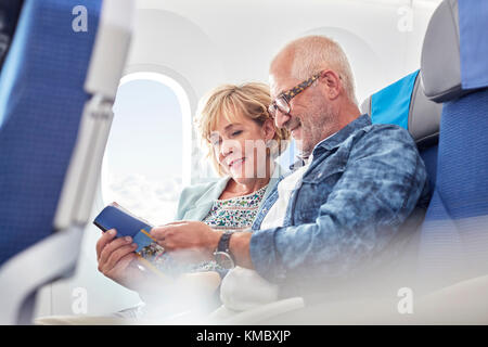 Mature couple reading guidebook on airplane Stock Photo