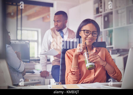 Portrait smiling confident businesswoman drinking green smoothie in office Stock Photo