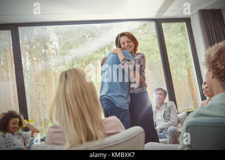 Man and woman hugging in group therapy session Stock Photo