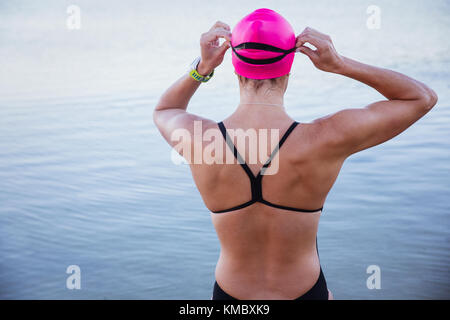 Female open water swimmer adjusting swimming goggles at ocean Stock Photo