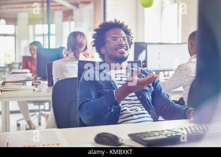 Businessman tossing tennis ball at desk in office Stock Photo