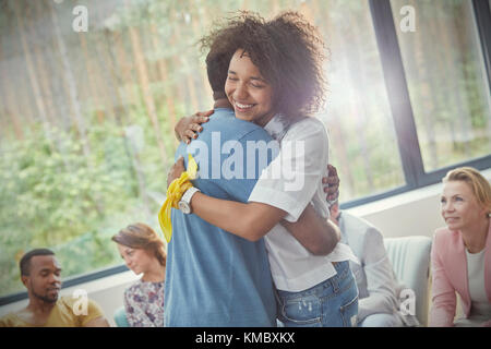 Smiling woman hugging man in group therapy session Stock Photo