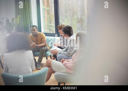 People listening to man in group therapy session Stock Photo