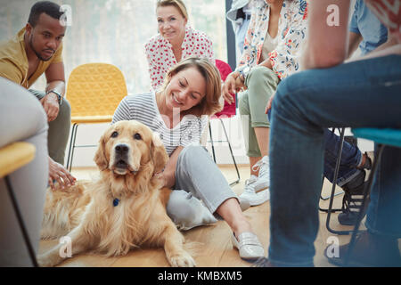 Woman petting dog in group therapy session Stock Photo
