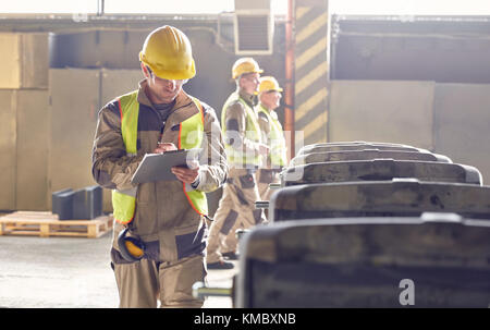 Steelworker writing on clipboard in steel mill Stock Photo