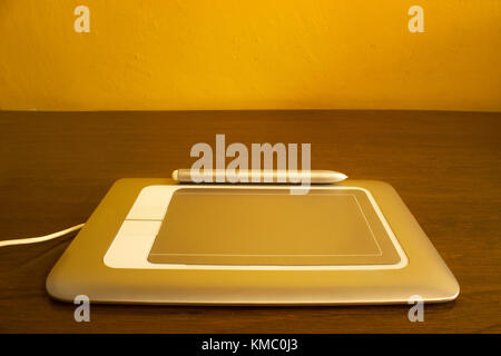 Horizontal photo of  silver pen tablet on a brown wood table Stock Photo