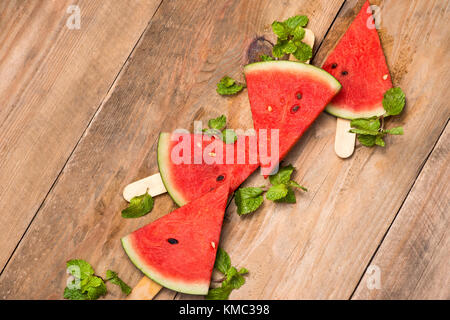 Watermelon slices on sticks. Watermelon popsicle on wooden white background. Top view, flat lay Stock Photo