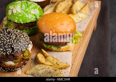 Closeup of set of three mini homemade Burger with marble beef and vegetables on a wooden Board. Stock Photo