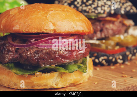 Closeup of set of three mini homemade Burger with marble beef and vegetables on a wooden Board. Stock Photo