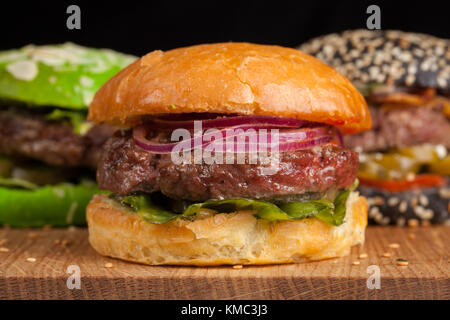 Closeup of set of three mini homemade Burger with marble beef and vegetables on a wooden Board. Stock Photo