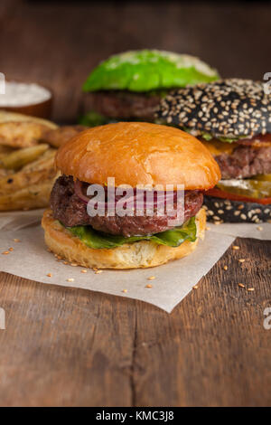 Closeup of set of three mini homemade Burger with marble beef and vegetables on a wooden Board. Stock Photo