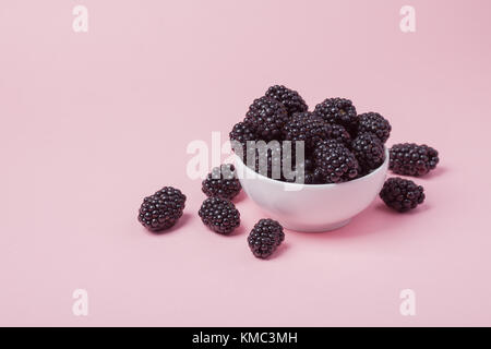 White bowl of fresh red raspberries on a pink background. Copy space. Stock Photo