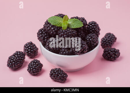 Closeup of a white bowl of fresh red raspberries on a pink background. Top view. Copy space. Stock Photo