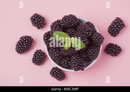 Closeup of a white bowl of fresh red raspberries on a pink background. Top view. Stock Photo