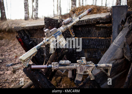 Assault rifles, painted in sand color on the background of the burnt logs. Airsoft. Stock Photo
