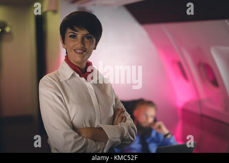 Air hostess standing with arms crossed Stock Photo