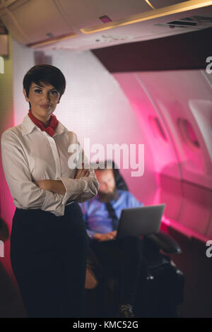 Air hostess standing with arms crossed Stock Photo