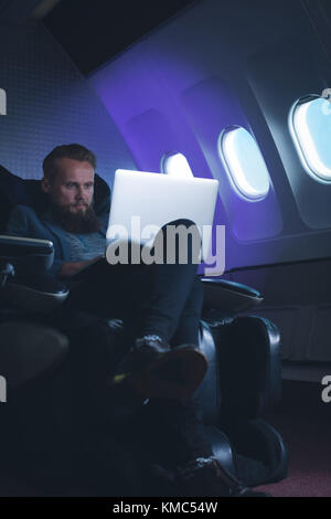 Businessman using laptop in airplane Stock Photo